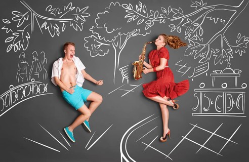 Love story concept of a romantic couple against chalk drawings background. Woman playing serenade
