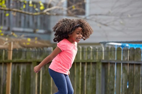 Kid toddler girl jumping on a playground in the backyard latin ethnicity