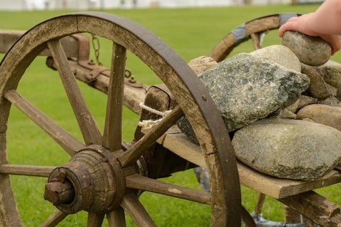Stones are loaded onto an old wooden cart - close-up