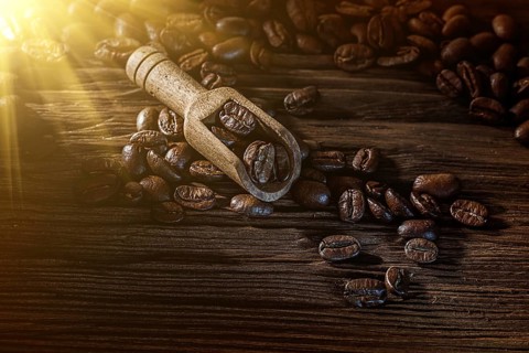 Coffee beans in scoop on vintage wooden board