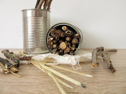 Homemade insect hotel made from tins, sticks and straw