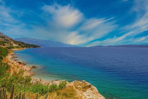 Coastal landscape with blue sea and green shore, peaceful sky with cloud patches, Makarska coast