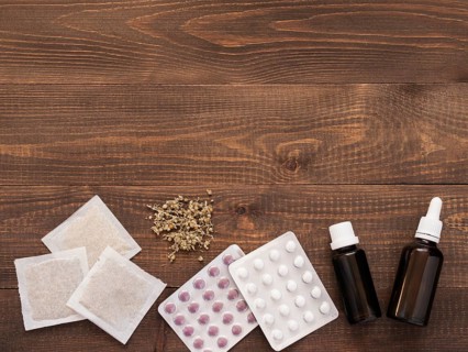 Tablets, drops and herbals on a dark wooden background with copy space. Flat lay or top view