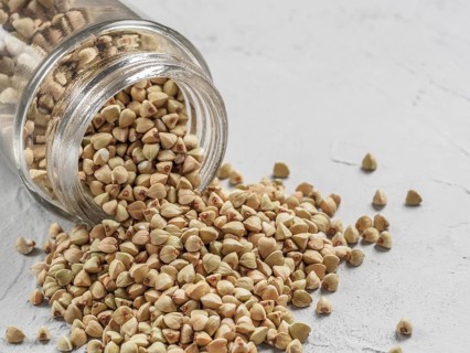 Raw green buckwheat in bank on gray background