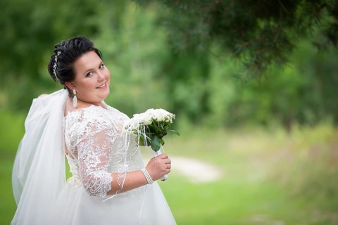 Fat bride with a wedding bouquet on a summer background