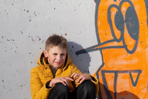 Boy teenager near the wall with funny graffiti