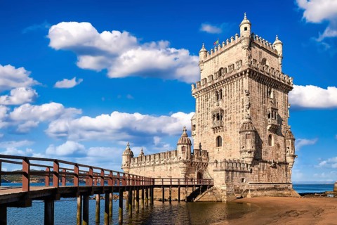 Belem tower and wooden bridge to it, Lisbon, Portugal at blue summer day sky with clouds. Medieval