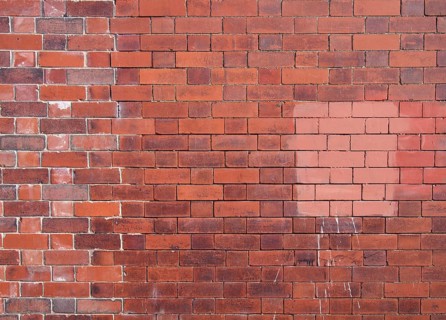 An old repaired patched exterior wall made of red bricks