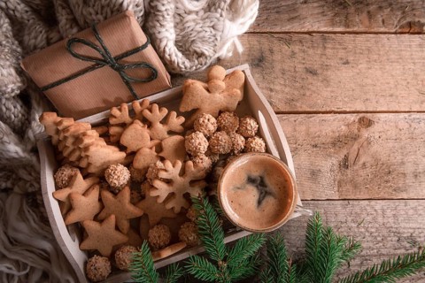 Cozy Christmas with a tray full of gingerbread, cookies and a cup of coffee, a fir twig, a gift,