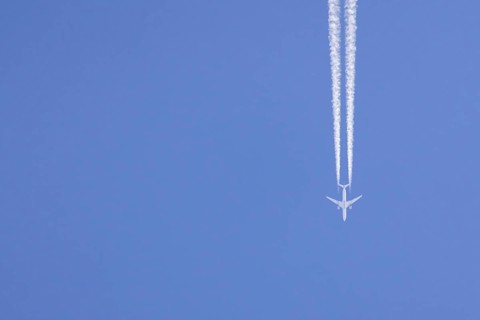 Airbus aircraft of Qatar airways flying across a blue sky with a vapour trail or contrail behind,