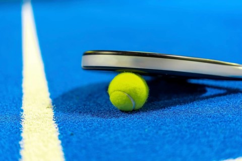 Close-up photo with copy space of paddle tennis racket on a ball
