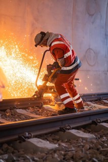 Construction worker grinding rails in a tunnel, sparks flying, rail welding, track construction