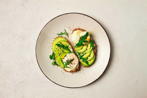 Sandwich with cream cheese, sliced avocado and boiled egg, arugula, on grainy bread, homemade,