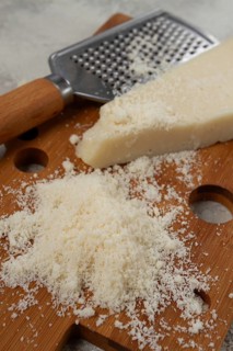 Freshly sliced and grated cheese, parmesan cheese, Gran gusto. Grana padano. on a wooden chopping