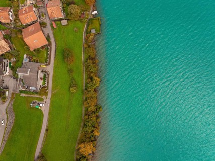 Aerial view of a lakeshore with green water, village and buildings along, Lake Brienz. Switzerland