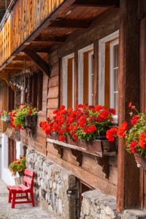 Wooden house with red geraniums in flower boxes in front of the windows, Lake Brienz, Brienz,