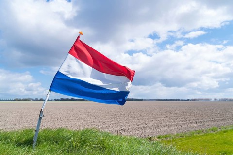 Waving dutch flag in a typical flat agricultural landscape