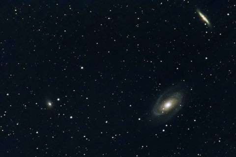 Two spiral galaxies (M 81 and M 82) and other galaxies, embedded in a star-studded deep space,