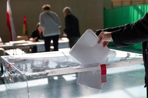 Voter's hand putting the vote into the ballot box.