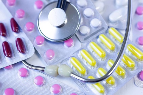 Blister packs with colorful pills alongside a stethoscope