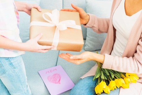 Daughter presenting gift box mom mother s day celebration