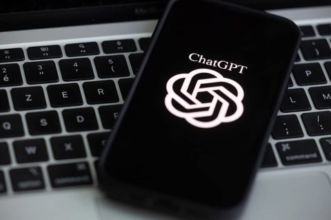 OpenAI software ChatGPT application on a mobile phone above a computer keyboard