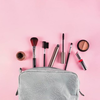 Makeup products spilling out bag pink background