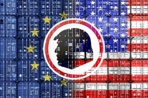Sign with silhouette of Donald Trump in front of stacked containers with European and US flags,
