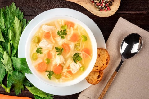 Chicken noodle soup, shot from the top on a dark rustic wooden background with a place for text