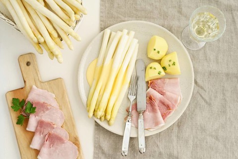Traditional German dish with white asparagus, boiled ham, hollandaise sauce and potatoes, served on