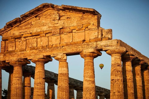 Sunset behind ancient columns of a temple with a clear sky, summer evening mood in Paestum, ancient