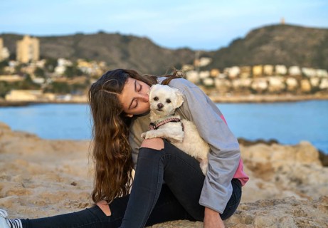 Girl playing with maltichon puppy dog in the beach