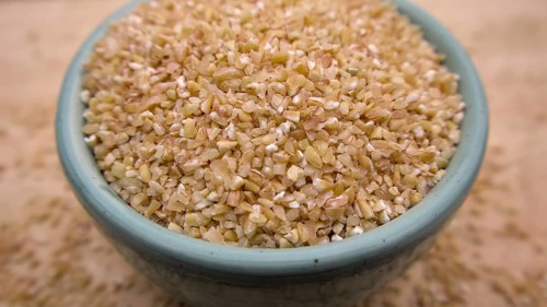 Broken Crushed Wheat (Dalia) in a Blue Bowl Isolated on Wooden Background, Close up