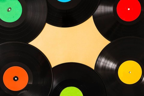 Overhead view colorful black vinyl record beige background