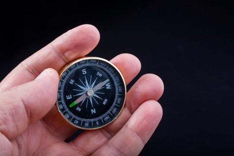 Child hand holding a compass on a black background