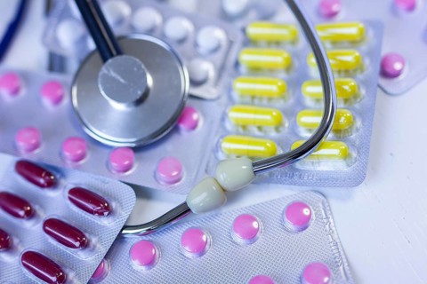 Various medication blister packs and a stethoscope on a table