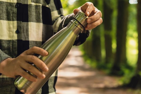 Close-up of Unrecognizable female hand holding Water bottle. Reusable steel thermo water bottle in