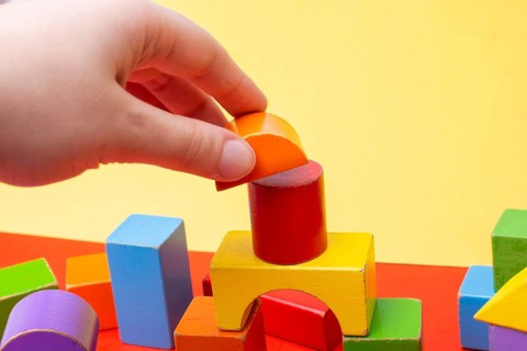 Hand building tower with colorful building blocks