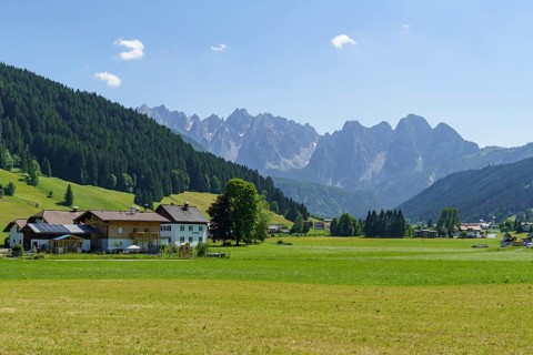 A small village surrounded by green meadows and mountains under a clear blue sky, Gosau, Austria,