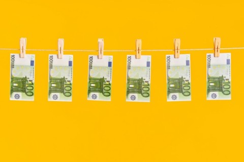 Money laundering, euro banknotes hanging on rope over yellow studio background. Finance,