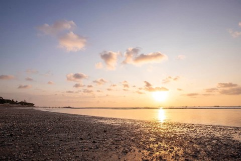 Dreamlike sunset on the dream beach of Kuta, small waves sunset over the sea and the reflection of
