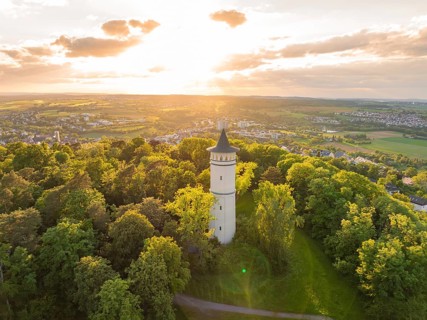 A tower rises in the sunset above the green forest and the vast countryside, Engelberg Tower,