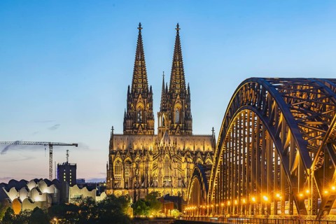 Cologne Cathedral, illuminated in the evening. Hohenzollern Bridge, railway bridge over the Rhine.