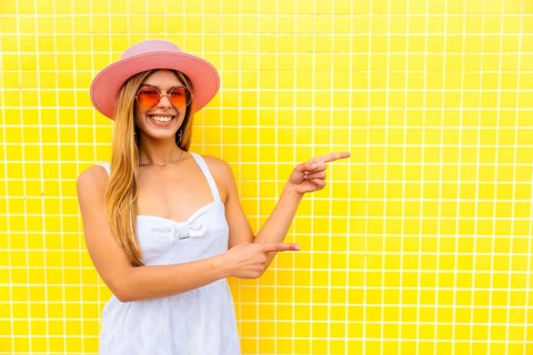 Fashionable woman indicating empty space on vibrant yellow background, ideal for showcasing