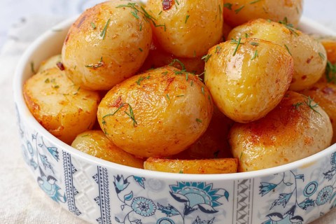 Baked new potatoes, with butter and dill, on a white plate, at home, no people