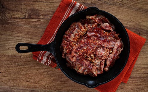 Crispy bacon, on a cast-iron skillet, on a wooden table, rustic style, no people
