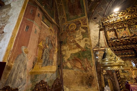 Richly decorated altar table and frescoes in a church showing detailed religious scenes, Thari