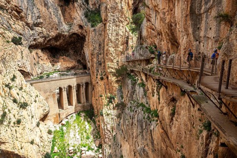 View of a viaduct and hikers on the Caminito del Rey path, embedded in a rocky gorge, Malaga,