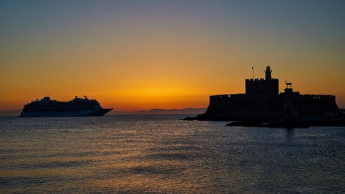 Cruise ship passing a fortress, calm, warm sky, sunrise, dawn, Fort of Saint Nikolaos, Mandraki