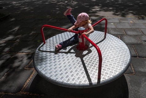 Outdoor shot, little girl, 3 years old, blonde, playing on a merry-go-round, children's playground,